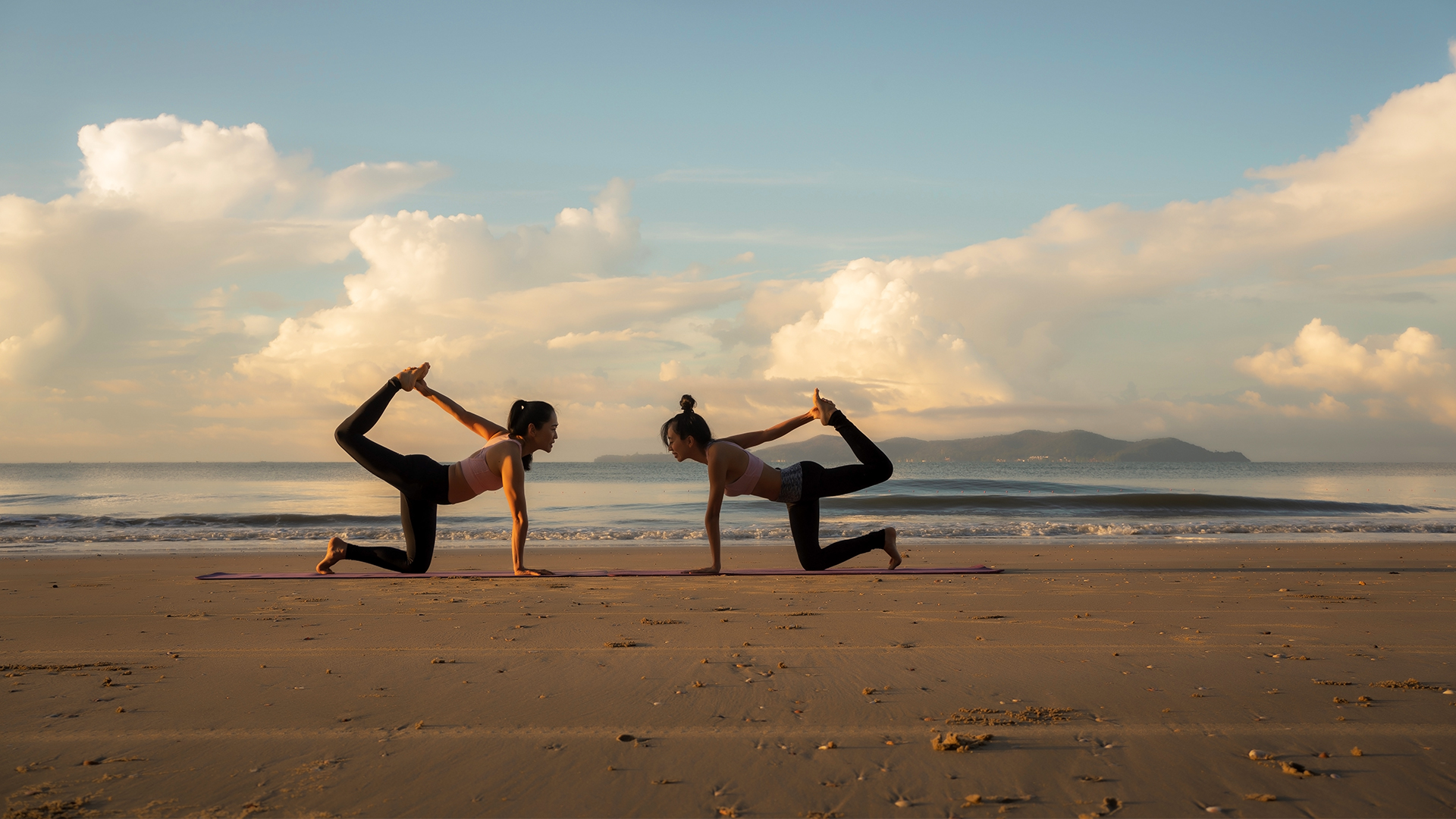 Mujeres haciendo yoga a la orilla de la playa