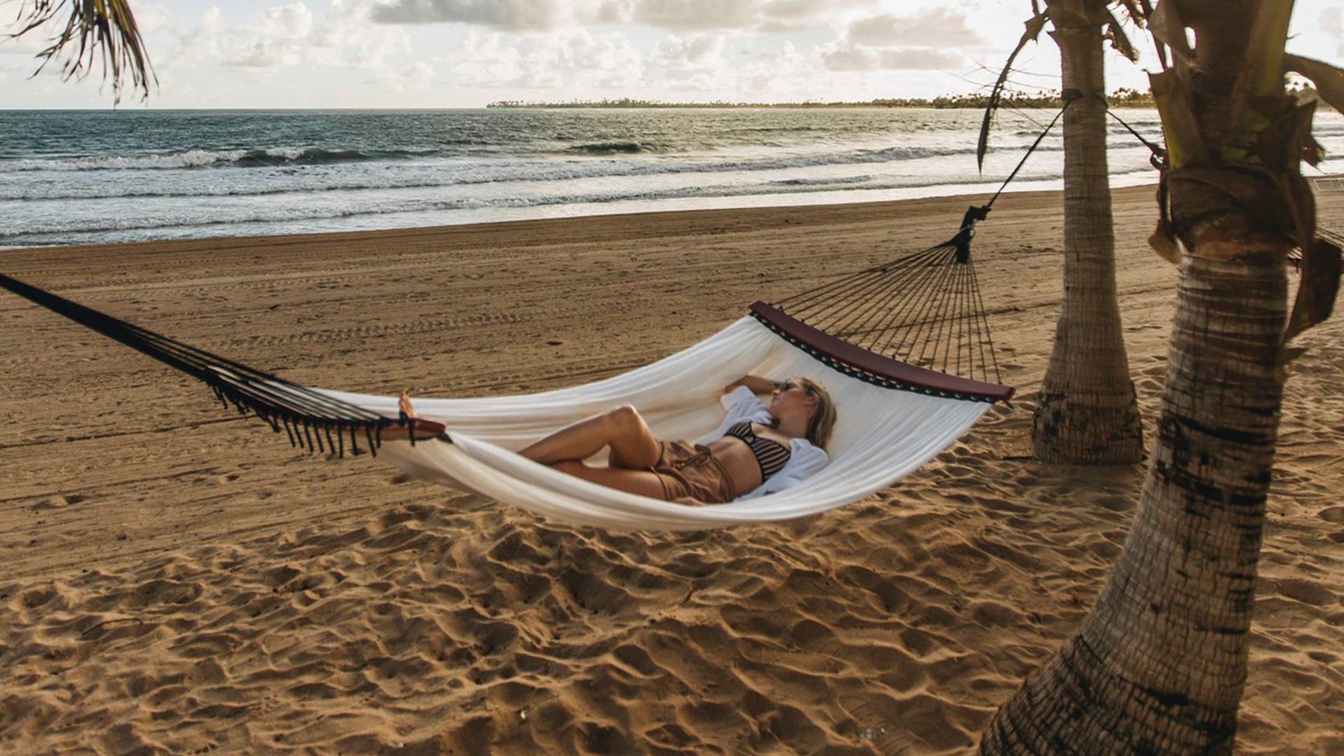 Mujer descansando en una hamaca en la playa