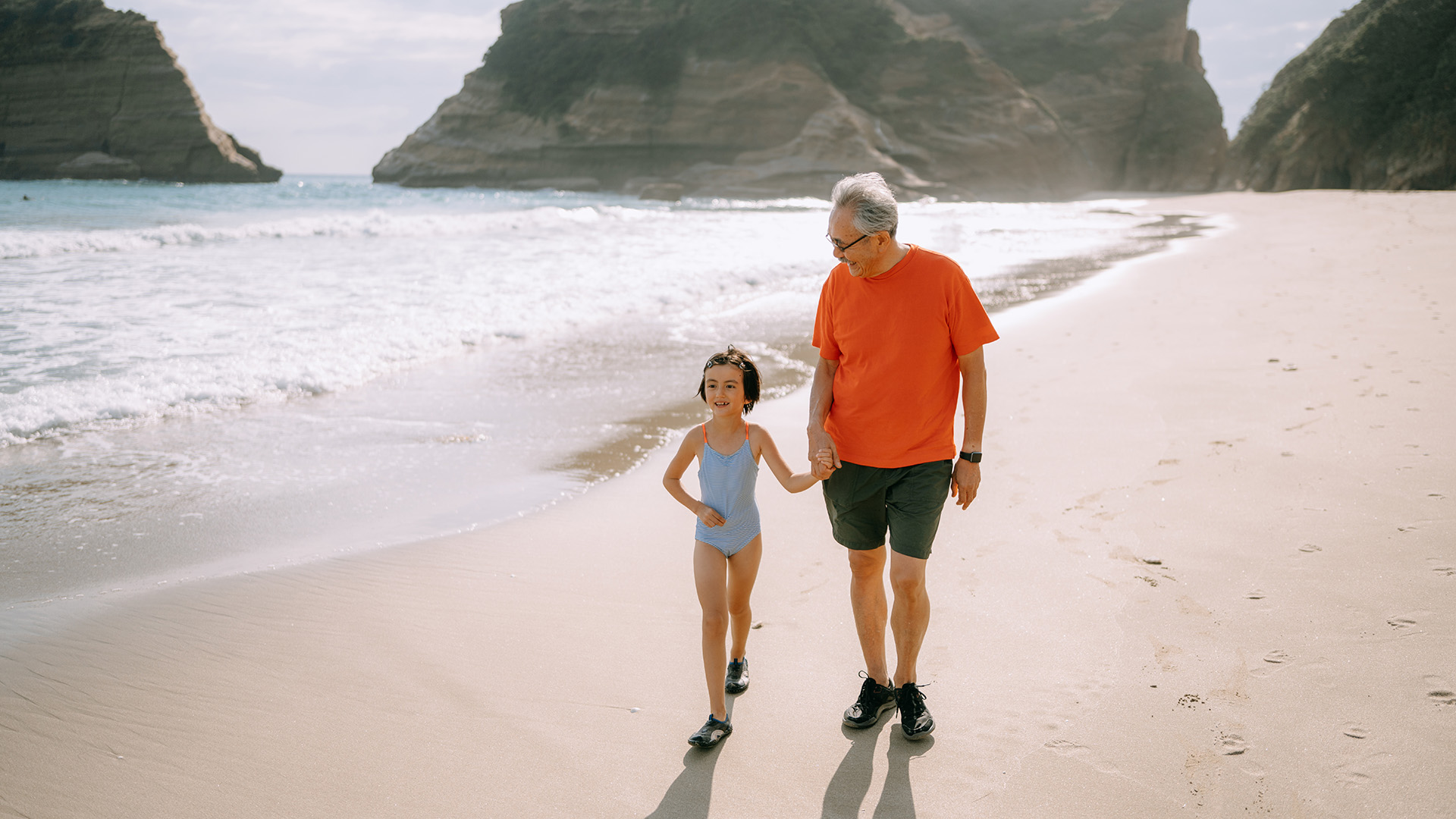 Abuelo y nieta caminando en la playa