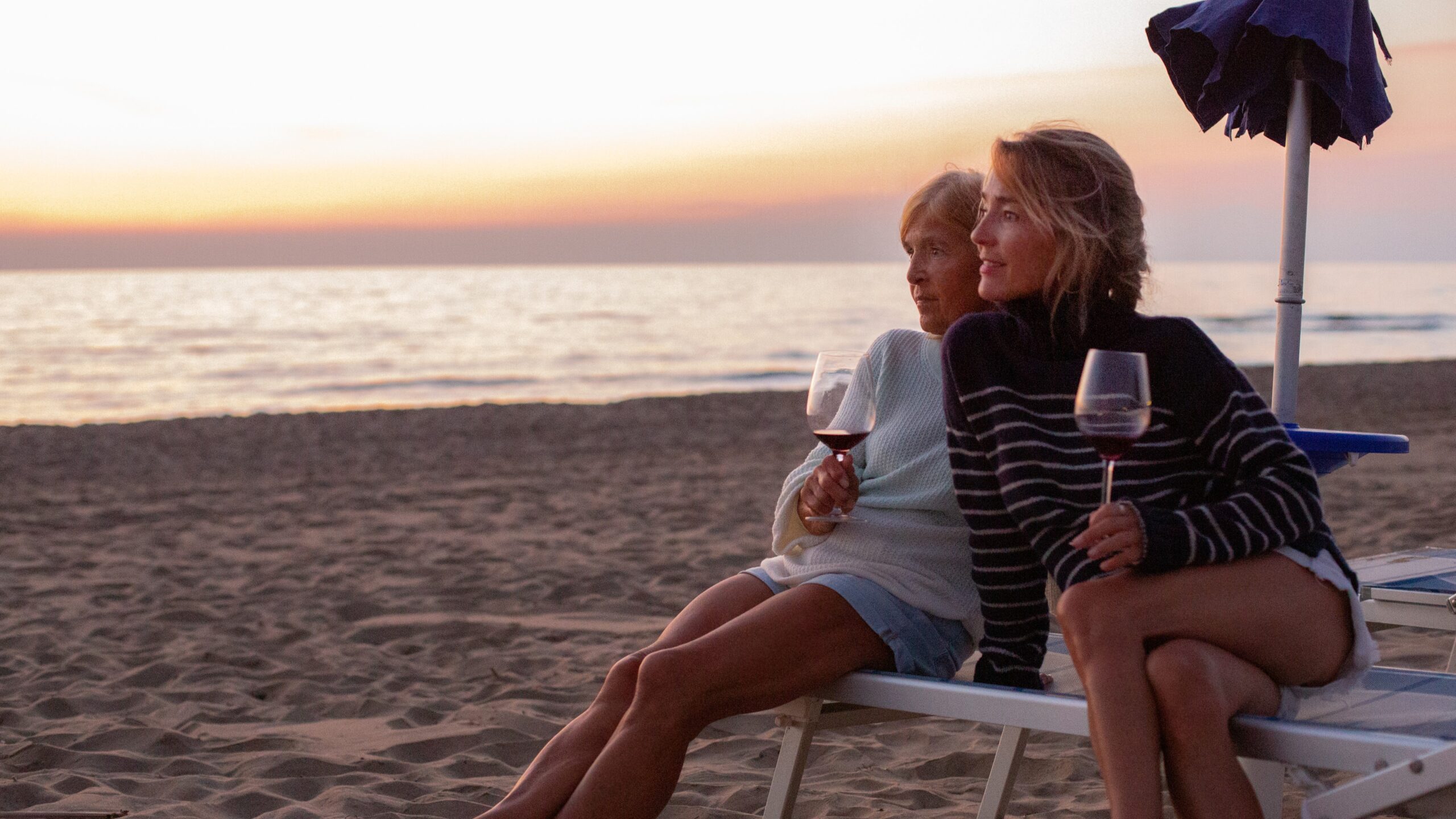 Madre e hija tomando una copa de vino en la playa