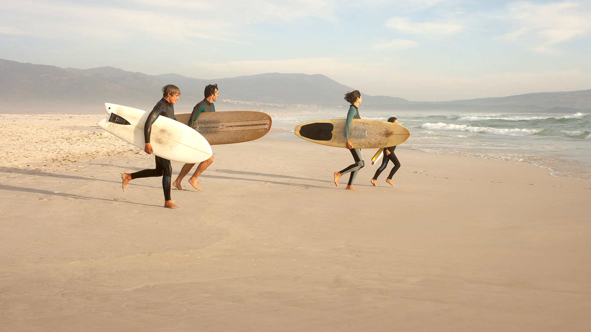 Grupo de personas entrando al mar para ir a surfear