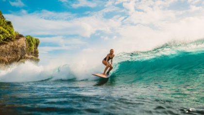 Female surfer riding a wave in Bali.