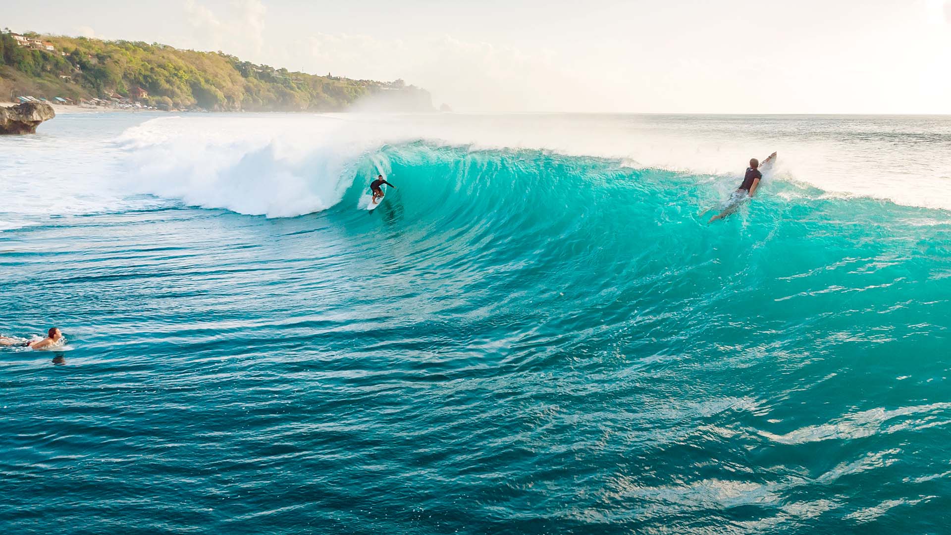 A wide shot of surfers riding a big wave in Bali.