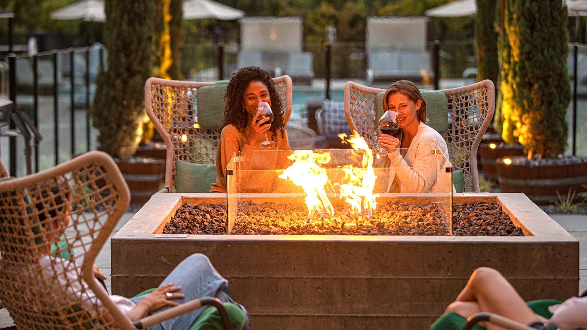 Girls with wine around pool deck firepit