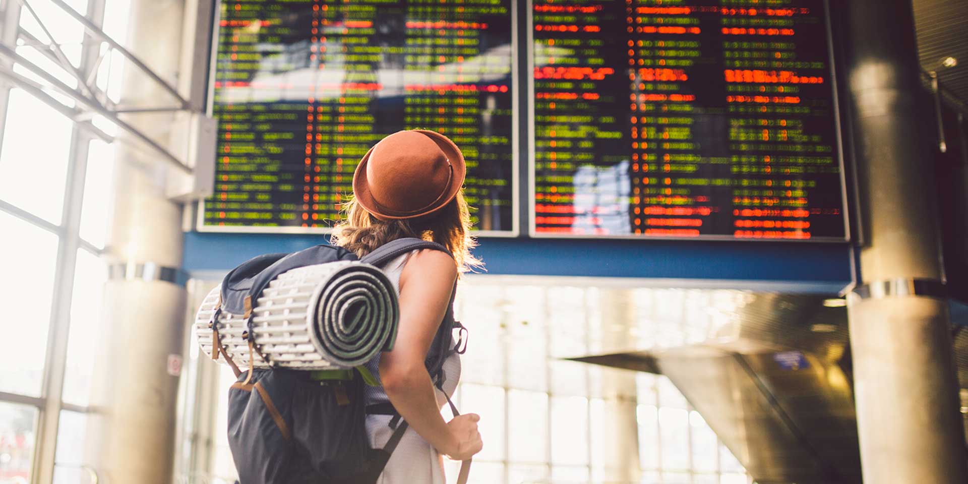 girl looking at flight cancellations board at airport