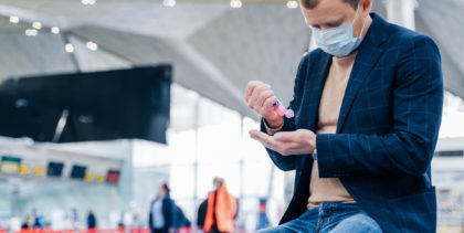man uses hand sanitizer at airport