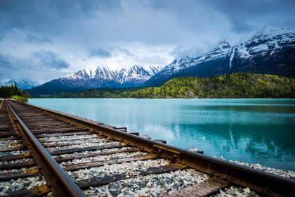 train tracks along water and mountains in colorado