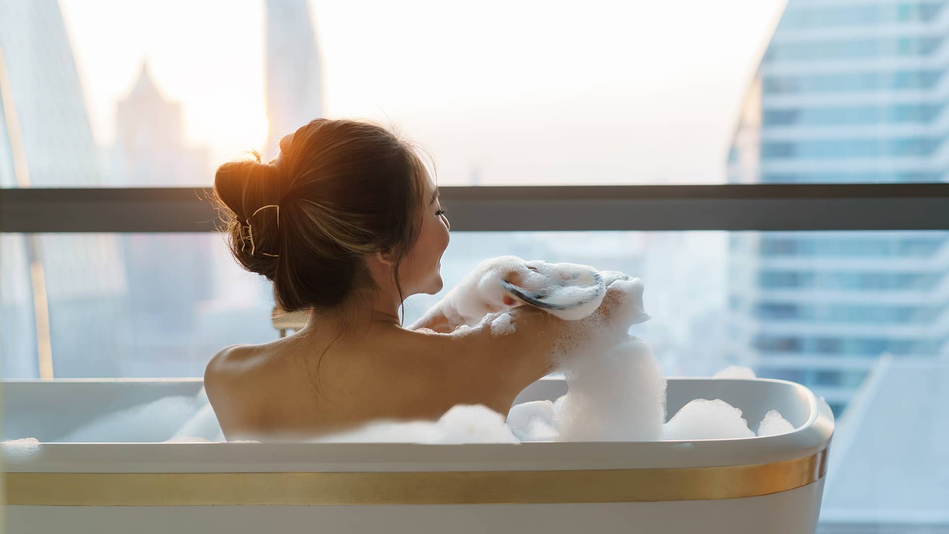 woman in bubble bath in front of large window