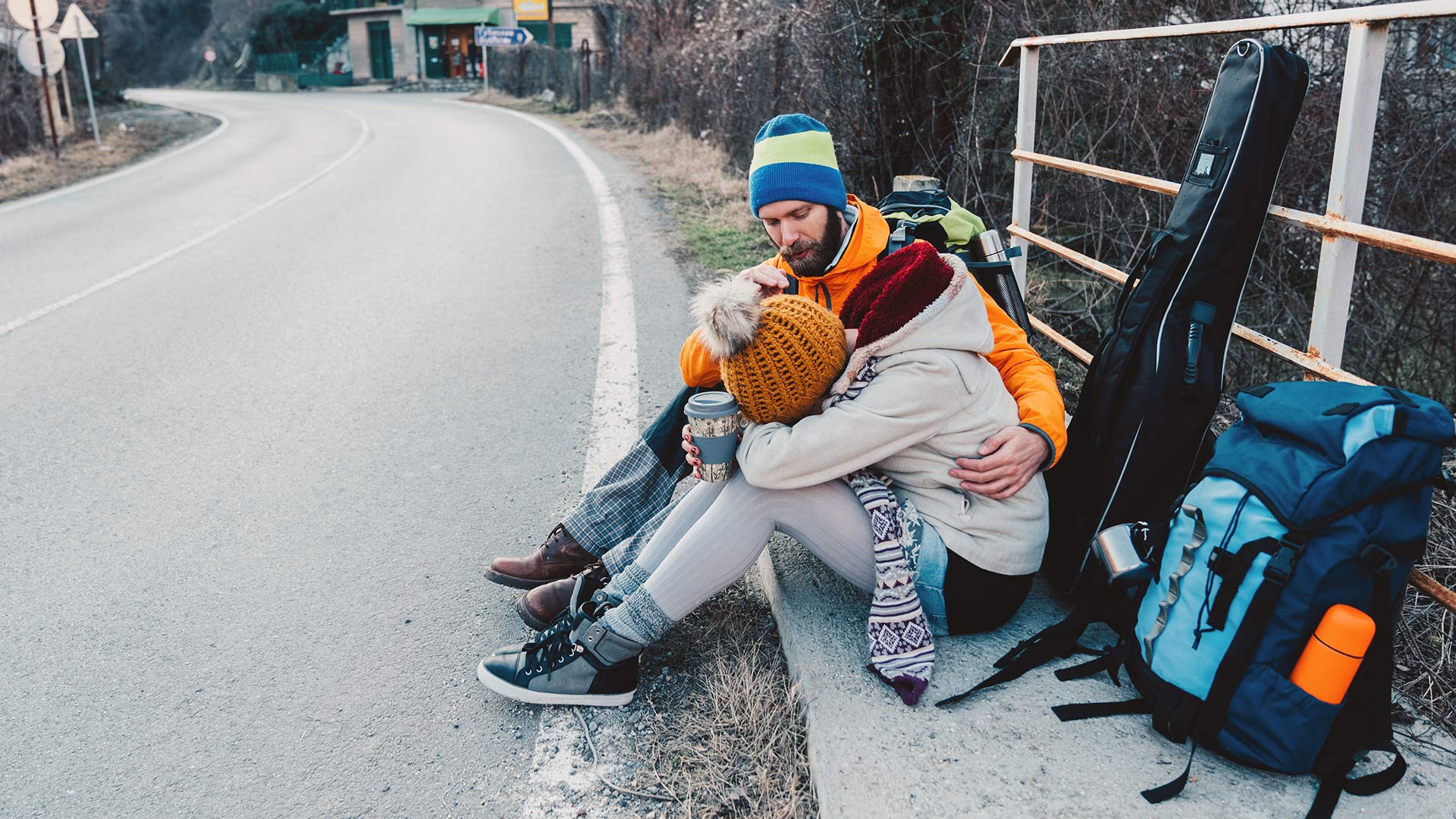 couple backpacking sitting on curb