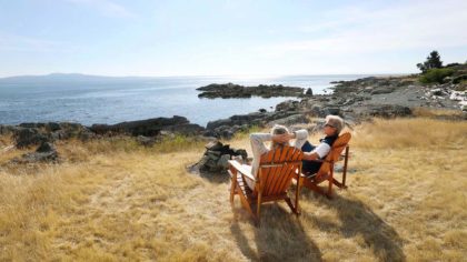 couple sitting on Adirondack chairs on coast in vancouver island