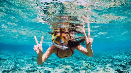 woman snorkeling making peace sign with hands