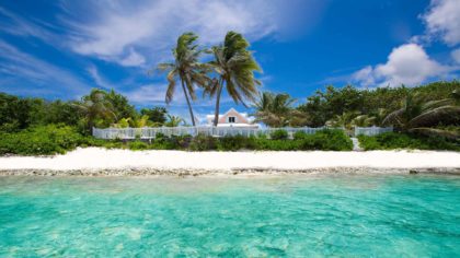 Ocean view cottage in Cayman Islands next to white sand beach and clear blue water.