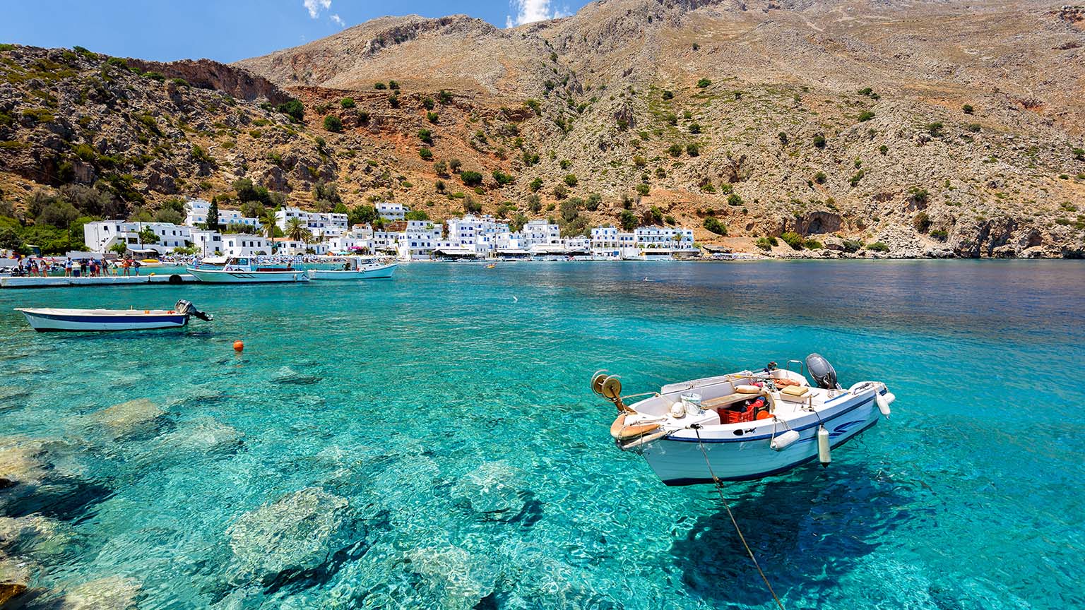 boat in water in front of small crete village