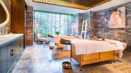 Treatment room with marble walls and wooden beds at The St. Regis Langkawi