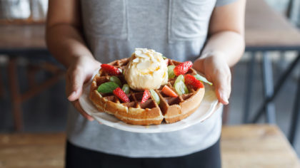 Person holding waffle topped with ice cream