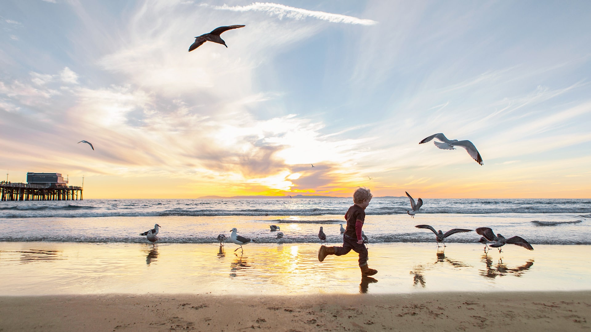 Child running on beach at sunset