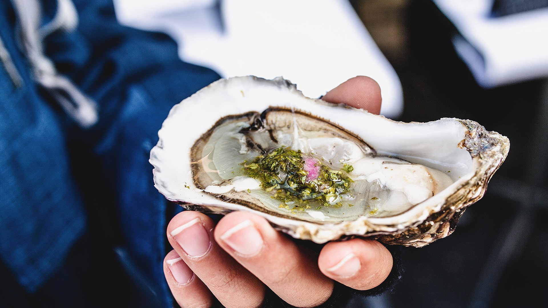 Fresh oyster with garnish being held