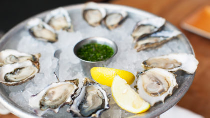 Fresh oysters on ice with lemon wedge