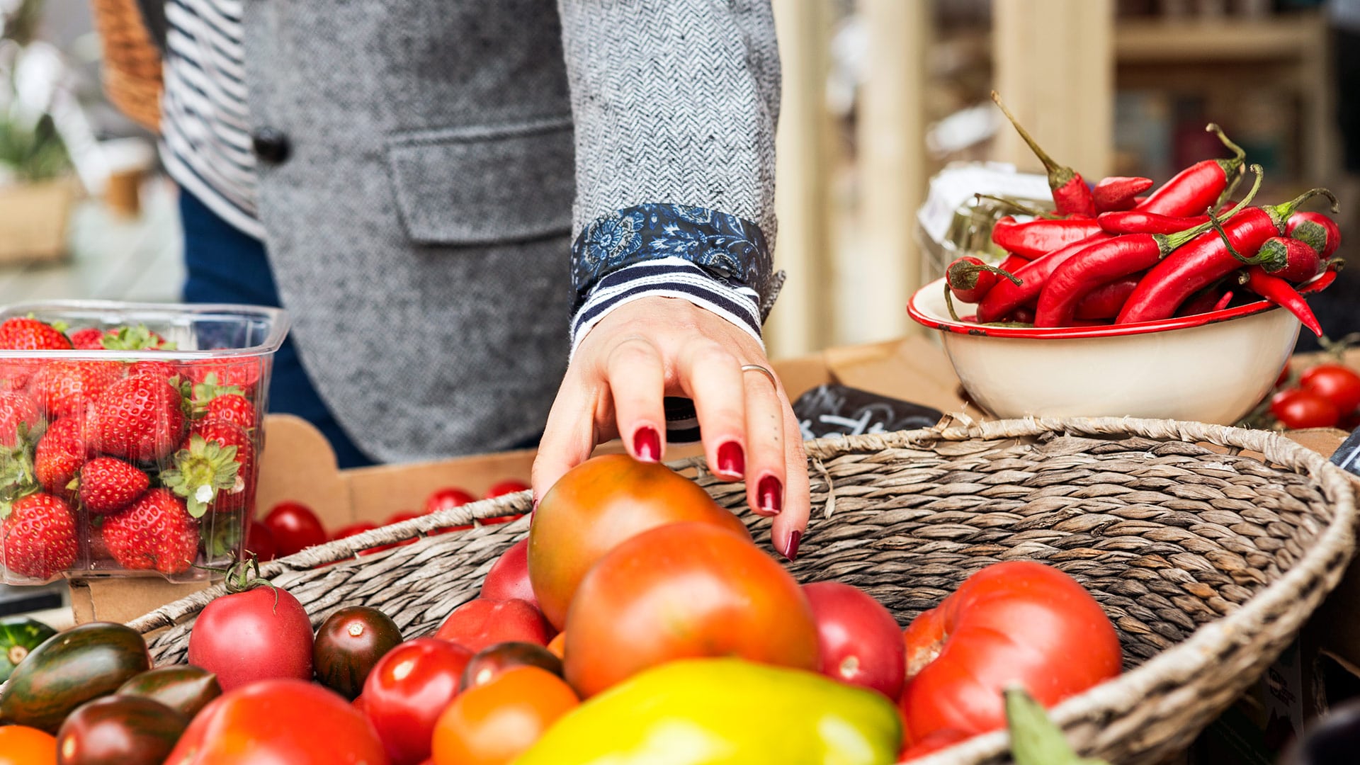 Woman picking up tomato from basket