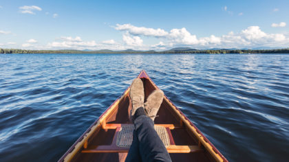 Person resting on a canoe in Lake Saranac