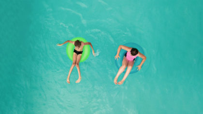 Two kids in inner tubes in pool