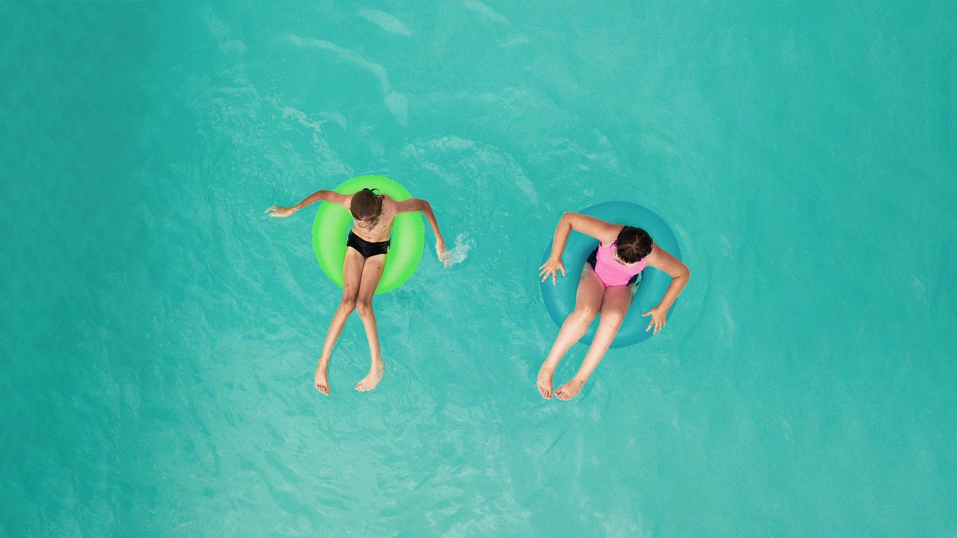 Two kids in inner tubes in pool