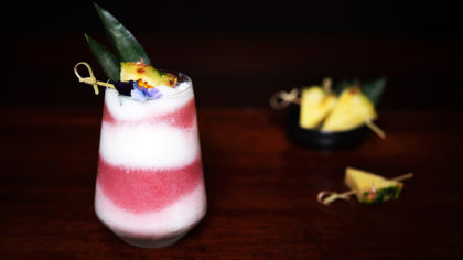 Frozen Miami vice with flower and pineapple garnish