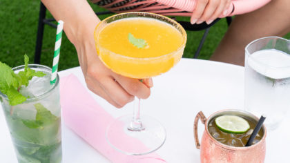 Person holding Orange cocktail and other drinks