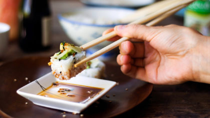 Person eating sushi roll with chopsticks