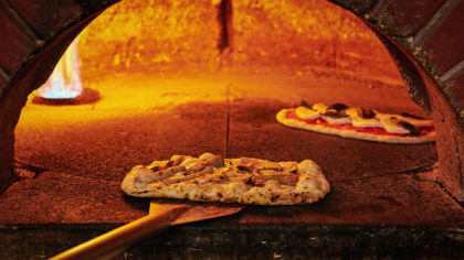 Fresh pizza being made in a brick oven