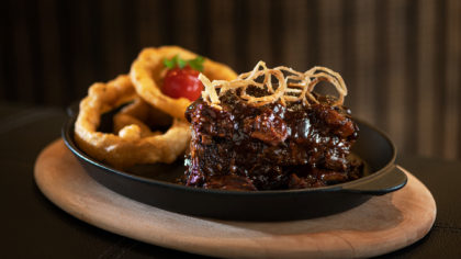 Short ribs and onion rings on a cast iron serving plate