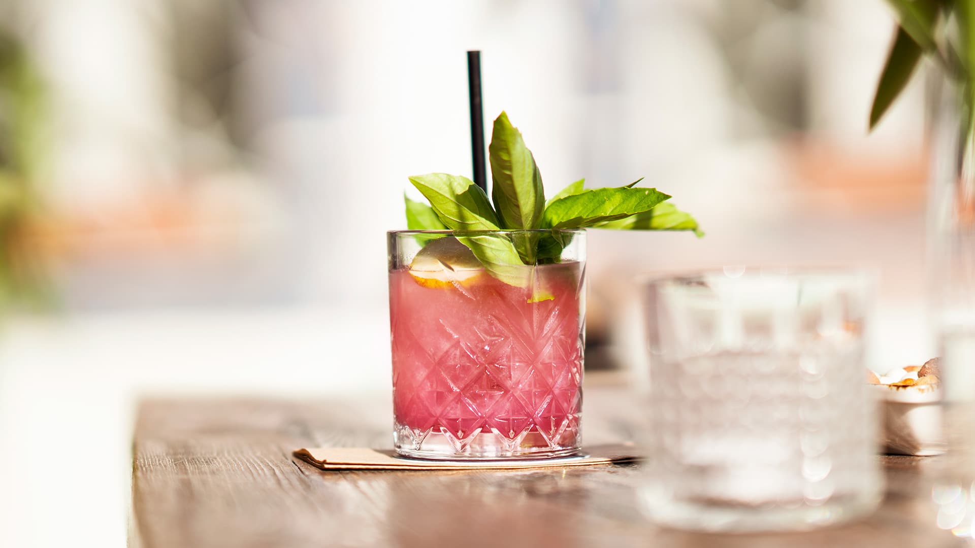 Pink fruit cocktail with a garnish and straw