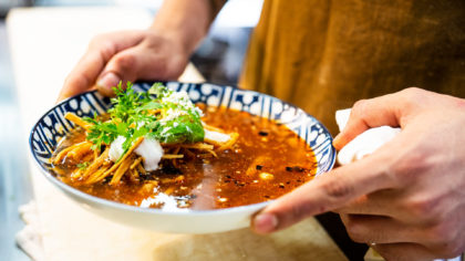 Person holding bowl of Mexican tortilla soup
