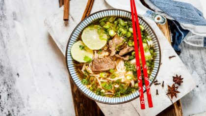 Pho with red chopsticks and limes