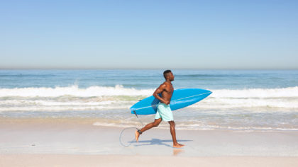 Man running with surfboard at beach