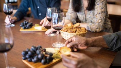 People tasting red wine grapes and cheese
