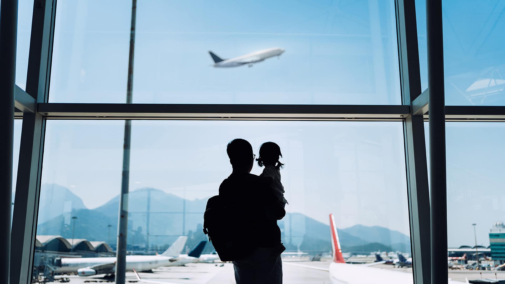 father and daughter looking at plane in airport