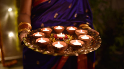 A person holding candles on a platter