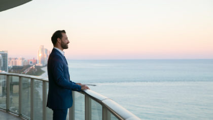 A man overlooks the beach from the hotel balcony