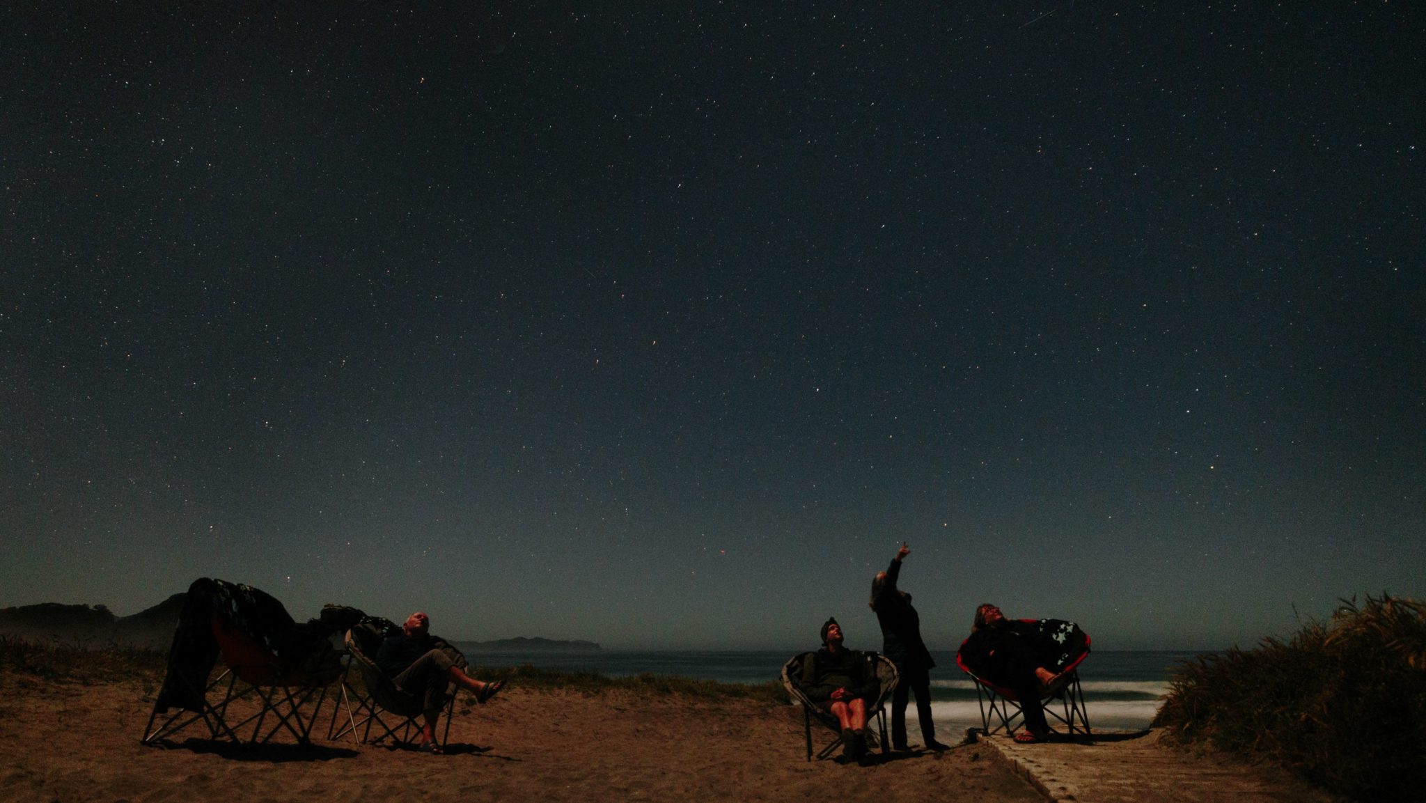 Stargazers admiring the starry night sky from the beach on New Zealand's Great Barrier Island.