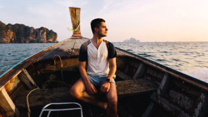 man taking a long tail boat ride in thailand