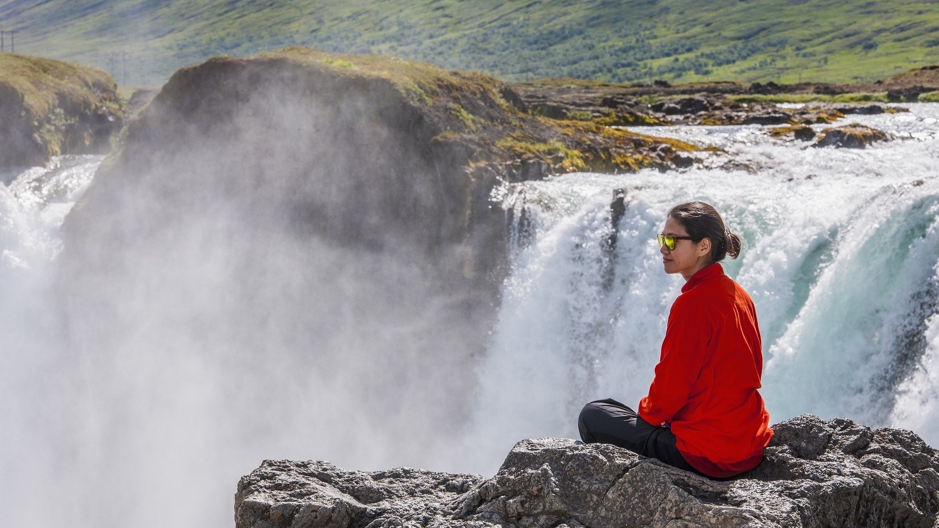 woman sitting on a rock above a waterfall in Iceland