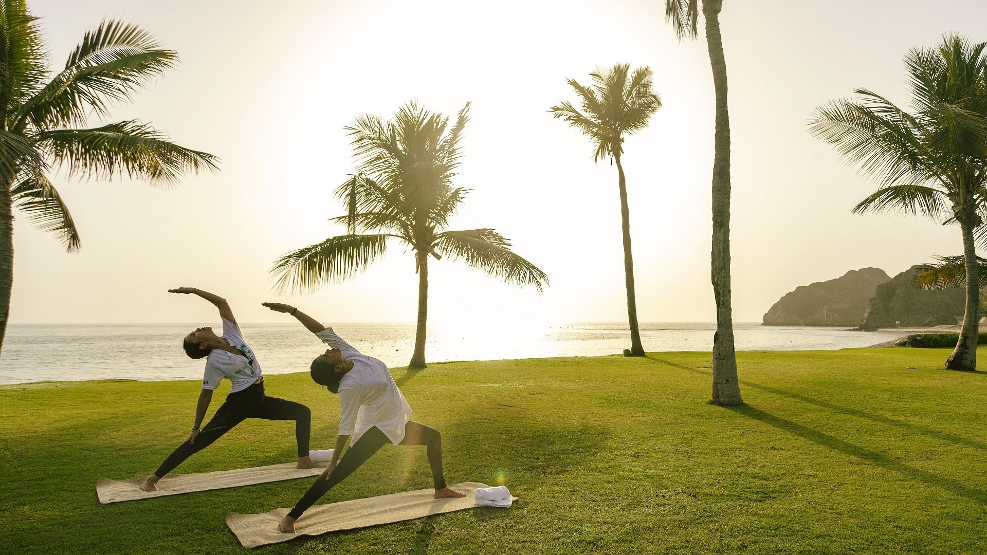 two women doing yoga at sunrise by the Gulf of Oman at al-Bustan Palace, a Ritz Carlton Hotel