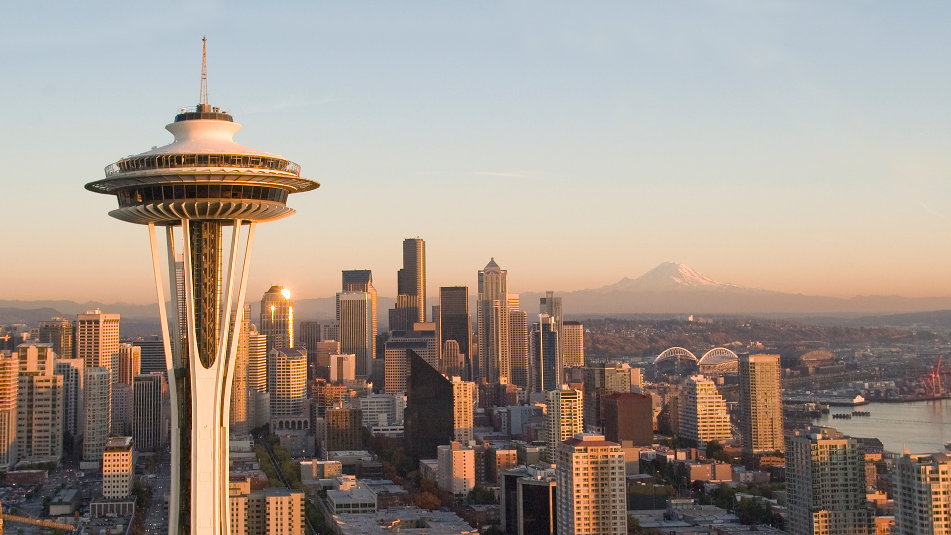 Seattle skyline, space needle and mountains at sunset