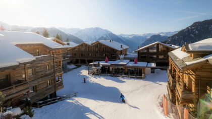 W Verbier wooden ski chalets, skiers skiing in