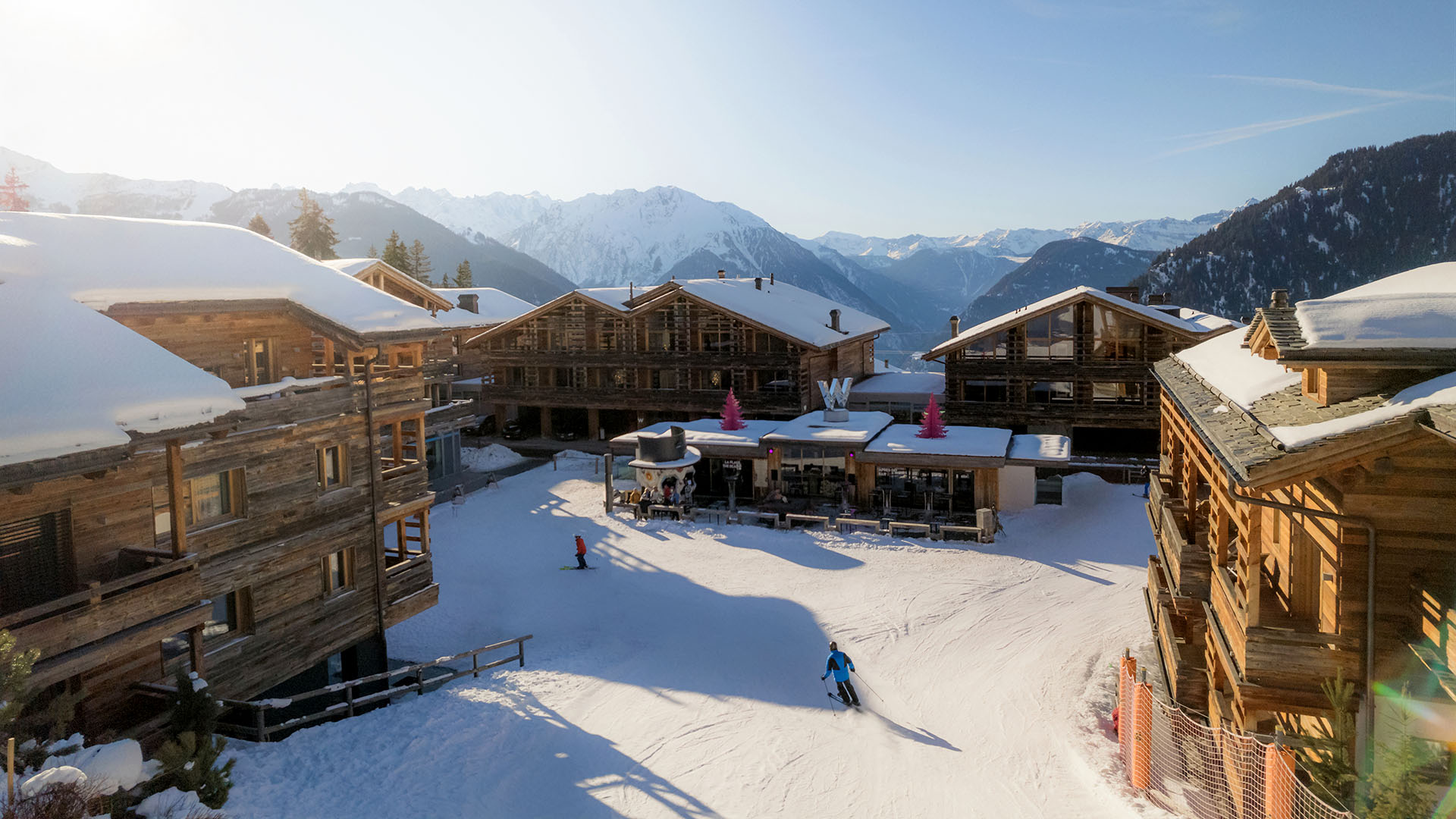 W Verbier wooden ski chalets, skiers skiing in
