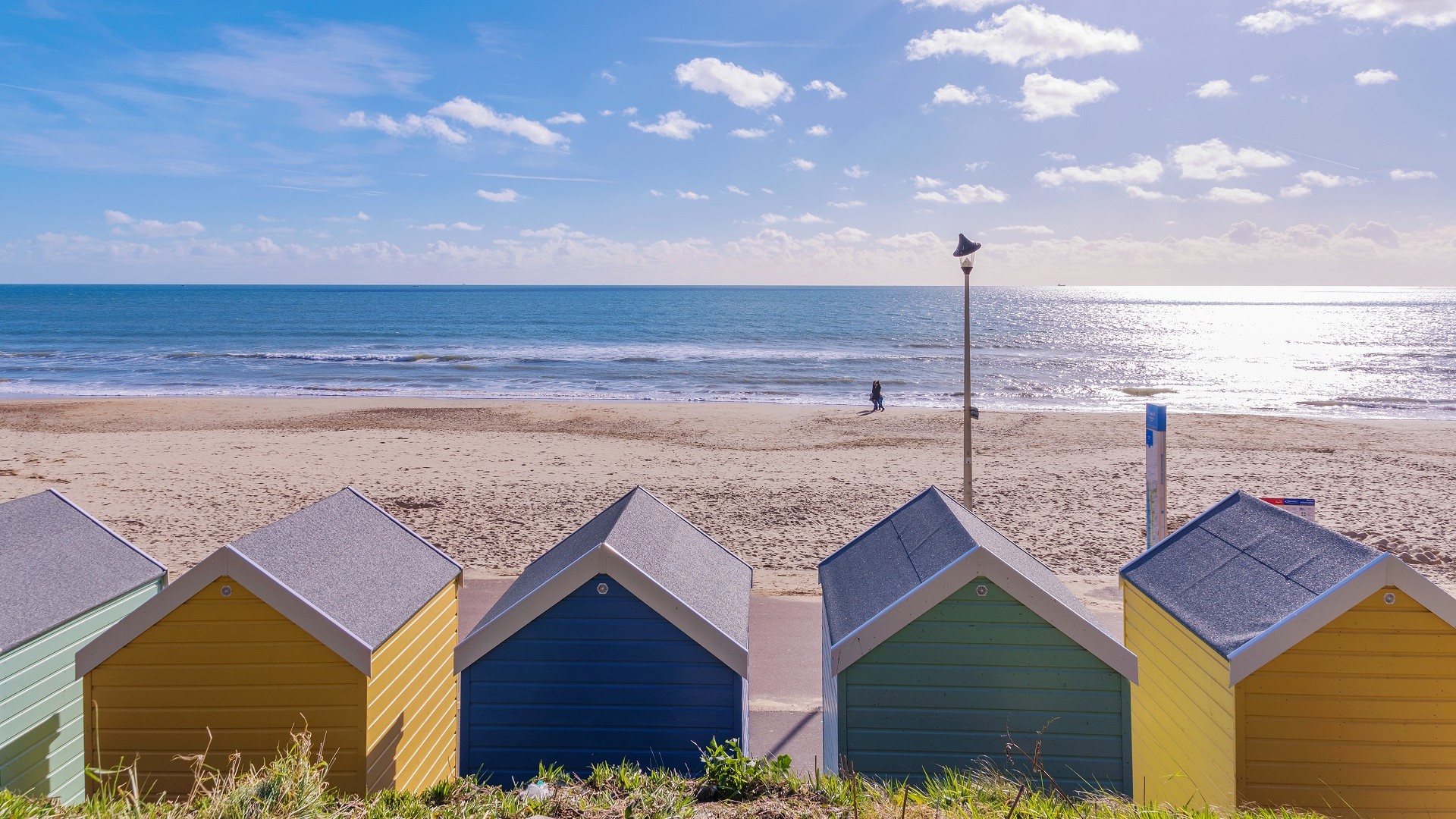 five colorful beach huts overlook a harbor on a sunny day