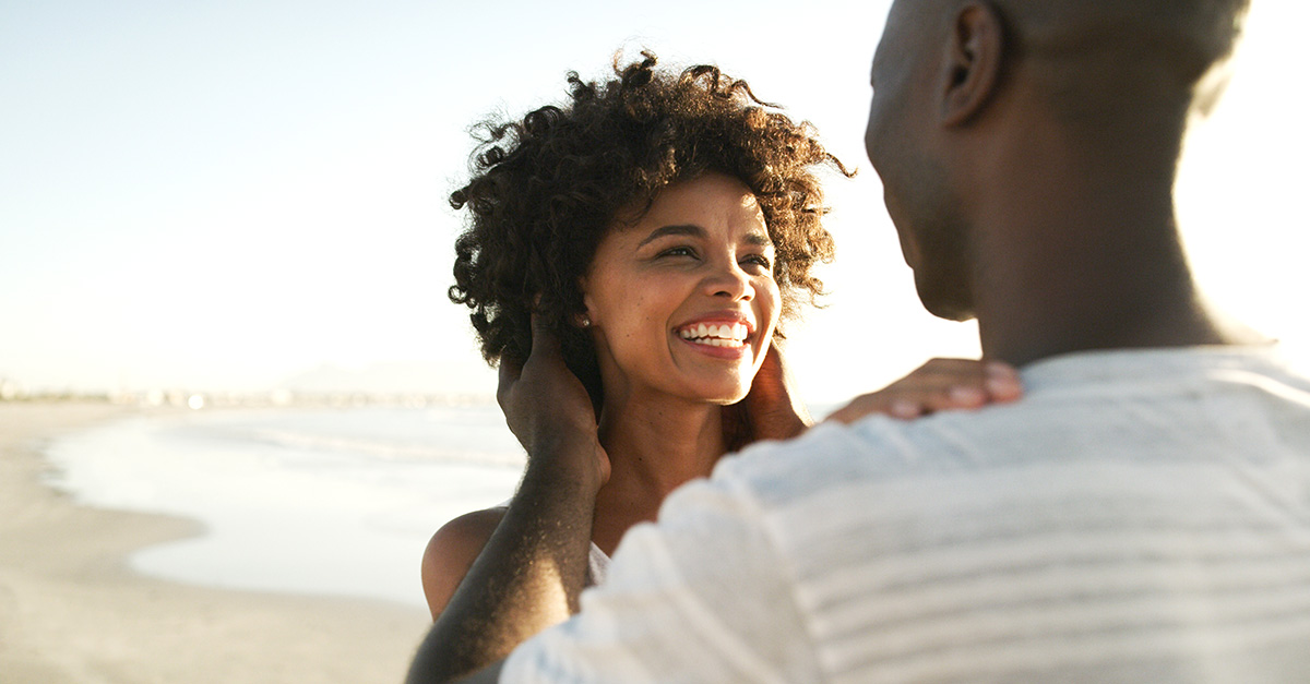 a smiling couple embrace on a beach