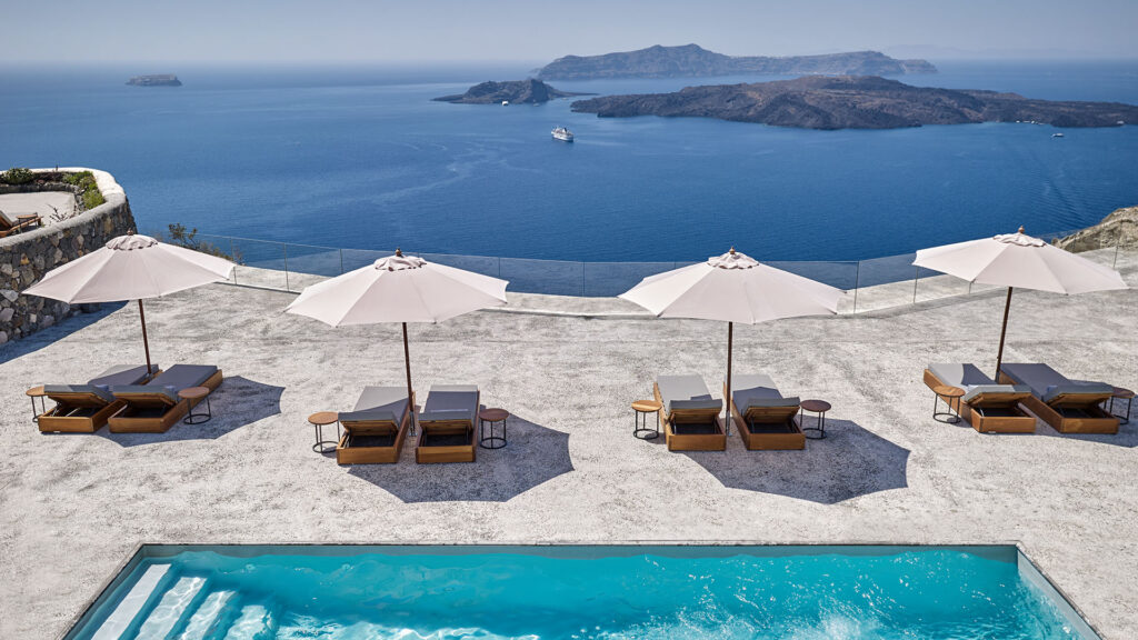 view of a swimming pool, loungers, and umbrellas overlooking the sea at Vedema, a Luxury Collection Resort, Santorini