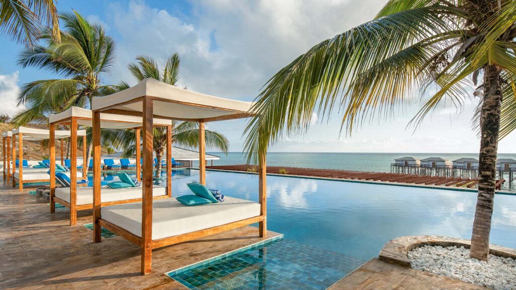 an outdoor swimming pool, cabanas, and palm trees at Le Mersenne, Zanzibar, Autograph Collection